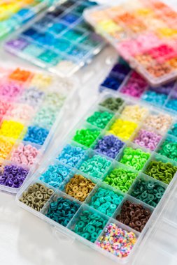 Beyaz bir masaya yerleştirilmiş çeşitli kil boncuk kutuları yaratıcı çocukların el sanatları projesini bekliyor..