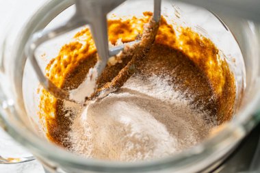 Lezzetli Portakallı Zencefilli Kurabiye Hamuru 'nun karışımına yavaş yavaş kuru malzemeler eklendi. Un ve baharatlar dengeli, baharatlı hamur dokusu için birleştirilir..