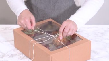 Elleri titizlikle bir kaseye taze kırmızı üzüm ekliyor, çeşitli peynirler, zeytinler ve pişirilmiş etlerle dolu güzel bir şarküteri kutusunu tamamlıyor.