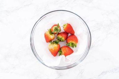 Taze yıkanmış ve kurutulmuş çilekler kağıt havluyla kaplı cam bir kasede dikkatlice düzenlenir. Atıştırmaya ya da daha fazla kullanılmaya hazır hale getirilir..