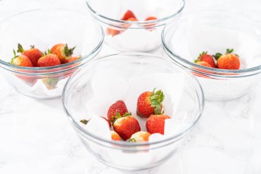 Parlak kırmızı çilekler, küf izleriyle karışmış, beyaz peçetedeki kağıt havluyla kaplı cam bir kasede dinleniyor, depolama tekniklerini gösteriyor..