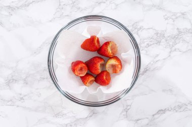 Taze yıkanmış ve kurutulmuş çilekler kağıt havluyla kaplı cam bir kasede dikkatlice düzenlenir. Atıştırmaya ya da daha fazla kullanılmaya hazır hale getirilir..