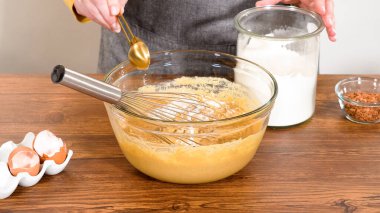 Bardak karıştırma kabında, büyük bir el çırpma ustalıkla lezzetli zencefilli kek ve karamel kremalı pasta malzemelerini karıştırır..