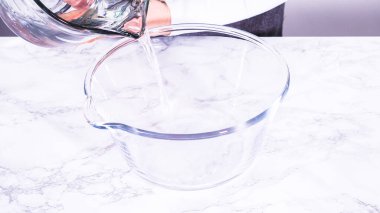 İçi su dolu geniş bir cam karıştırma kabı olgun çilekleri nazikçe temizlemek için hazır bekliyor. Kurumadan ya da depolamadan önce el değmemiş olduklarından emin olmak için..