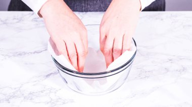 Çilekler, yeni yıkanmış ve kurutulmuş, cam bir kasede güzelce depolanmış kağıt havluyla kaplanmış ve tazeliği korumak için plastikle kaplanmış..