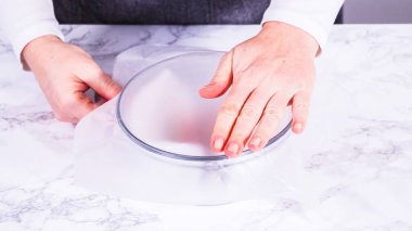 Çilekler, yeni yıkanmış ve kurutulmuş, cam bir kasede güzelce depolanmış kağıt havluyla kaplanmış ve tazeliği korumak için plastikle kaplanmış..