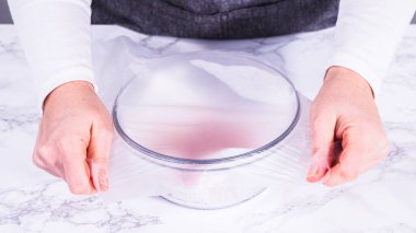 Çilekler, yeni yıkanmış ve kurutulmuş, cam bir kasede güzelce depolanmış kağıt havluyla kaplanmış ve tazeliği korumak için plastikle kaplanmış..