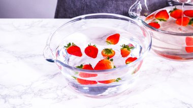 Olgun çilekler, depolama veya tüketimden önce temizlik ve uzun ömürlü olmak için meyveyi yıkamada bir adım olarak büyük bir bardakta karıştırma kabında suya gömülür..