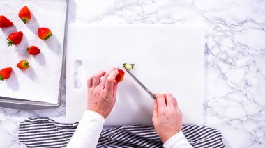 Düz yatıyordu. Lezzetli kırmızı çilekler, bazıları erken bozulmayı gösteriyor, beyaz bir kesme tahtasının üzerine yerleştirilmiş, güvenli bir şekilde tutulmuş, yanında kağıt havlu kaplı cam bir kase,