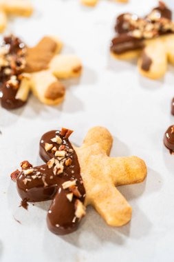 Çikolataya batırılmış ve fındık ezmesi ile süslenmiş kar tanesi şeklindeki kesme şekerli kurabiyeler yaratmak. Parşömen üzerinde zarif bir şekilde sunulmuş..