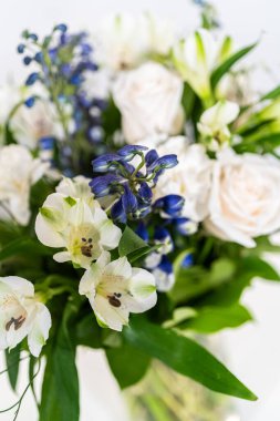 Taze beyaz güllerin ve çeşitli çiçeklerin bulunduğu büyüleyici bir buket, zarif bir vazoda düzenlenmiş, zamansız bir güzellik yayıyor..