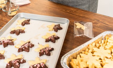 Dikkatlice paketlenmiş Noel kurabiyeleri, çikolataya batırılmış ve şeffaf selofan ambalajla sunulmuş, bayram hediyesi olarak mükemmel..