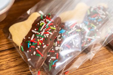 Dikkatlice paketlenmiş Noel kurabiyeleri, çikolataya batırılmış ve şeffaf selofan ambalajla sunulmuş, bayram hediyesi olarak mükemmel..