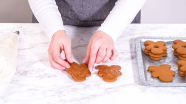 Zencefilli kurabiyeler mermer yüzeyde ikinci yarılarını beklerler, her biri lezzetli sandviçler yapmak için tereyağlı kremayla titizlikle borular. Boruların hassasiyeti şenlikli bir dokunuş katıyor..