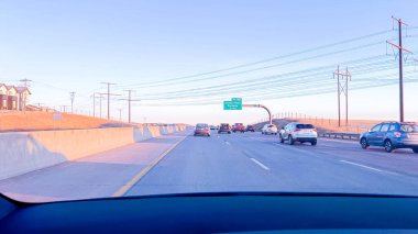 Denver, Colorado, USA-January 26, 2024-Vehicles are lined up during the morning rush-hour on a highway leading from suburban areas towards Denver, with the golden hues of sunrise illuminating the clipart