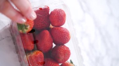 Taze çilekler, mutfak tezgahında dinlenen ve yıkanmaya, yenmeye ya da saklanmaya hazır orijinal plastik konteynerlerinde sergilenir..