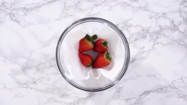 Çilekler, yeni yıkanmış ve kurutulmuş, cam bir kasede güzelce depolanmış kağıt havluyla kaplanmış ve tazeliği korumak için plastikle kaplanmış..