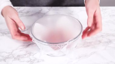 Çilekler, yeni yıkanmış ve kurutulmuş, cam bir kasede güzelce depolanmış kağıt havluyla kaplanmış ve tazeliği korumak için plastikle kaplanmış..