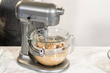 Çikolatalı Zencefilli Kurabiye Hamuru 'nun malzemelerini karıştırmak için kullanılan bir tezgah. Karıştırma işlemi devam ediyor, zengin ve pürüzsüz bir kurabiye hamuru yaratıyor.