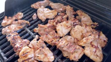 Salamura edilmiş tavuk butları küçük bir Weber ızgarasının ızgarasında cızırdar, havayı iştah açıcı bir koku ve hafif bir dumanla doldurur..