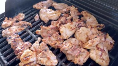 Salamura edilmiş tavuk butları küçük bir Weber ızgarasının ızgarasında cızırdar, havayı iştah açıcı bir koku ve hafif bir dumanla doldurur..