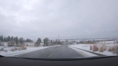 Denver, Colorado, ABD-26 Ocak 2024 - Sabah erken saatlerde yeni inşa edilmiş bir banliyö mahallesine sessiz bir sürüş getiriyor, yolu kaplayan taze kar ve karanlık bir gökyüzü altında evler.