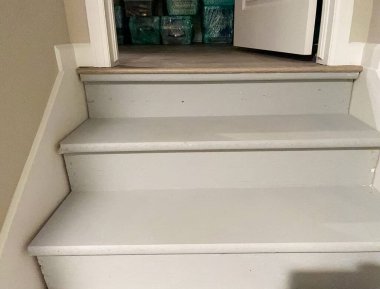 Kapalı alanda boyanmış ahşap bir merdivenin yakın çekim görüntüsü. Beyaz boyalı lastik izleri ve basamaklarla temiz bir tasarım sergiliyor. Yenileme, yenileme veya iç tasarım ilham kaynağı için ideal.