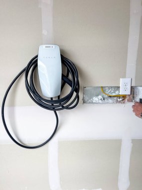 Castle Rock, Colorado, ABD-22 Mart 2023-Residential garaj duvarı altında düzgünce sarmalanmış bir Tesla elektrikli araç şarj aleti var. Alçıpan inşaatı görülebilir