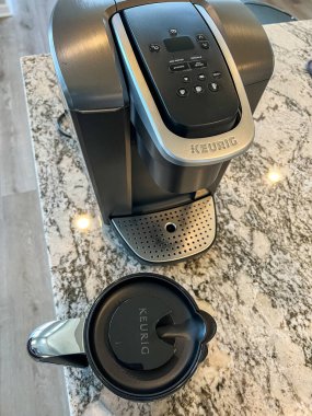 Castle Rock, Colorado, ABD-Nisan 18, 2023-Keurig kahve makinesi modern bir mutfaktaki parlak granit tezgahın üzerine yerleştirildi. Kahve makinesi, Keurig kahve fincanının yanında kapaklı olarak gösteriliyor.