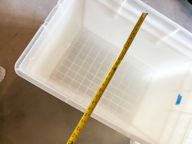 Castle Rock, Colorado, ABD-29 Mayıs 2023 yakın çekim görüntüsü temiz bir plastik kabın içinde derinliğini belirlemek için sarı bir mezura gösteriyor. Ölçüm yaklaşık 2.5 inç gösteriyor. Şey...