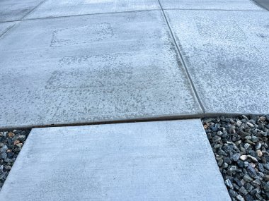 Beton kaldırım ve garaj yolu düzensiz bölümleri ve düzensizliği gösteriyor. Taşınma veya düzensiz kurulum nedeniyle potansiyel çelme tehlikesi ve drenaj sorunları