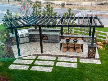 Castle Rock, Colorado, ABD-14 Mayıs 2023-A şık bir açık hava mutfağı ve şık bir pergola, dahili ızgara ve bar oturma alanı. Veranda zarif kaldırımlarla tasarlandı ve etrafı sarıldı.