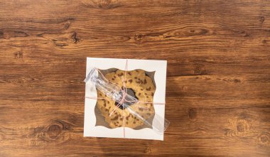 Düz yatıyordu. Tuzlu karamel şekerlemeleri ve zencefilli ekmek parçacıklarıyla süslenmiş zencefilli keki dikkatlice hediye etmek için açık pencereli beyaz bir kağıt bohça kek kutusuna yerleştiriyorum..