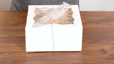 Tuzlu karamel şekerlemeleri ve zencefilli ekmek parçacıklarıyla süslenmiş zencefilli keki dikkatlice hediye etmek için açık pencereli beyaz bir kağıt bohça kek kutusuna yerleştiriyorum..