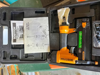 Süpürge, Colorado, ABD-2 Mart 2024-A Bostitch çivi tabancası siyah bir plastik çantanın içinde saklanır çivi tabancası siyah aksanlı ve kullanma kılavuzu ve parçaları ile birlikte gelir.