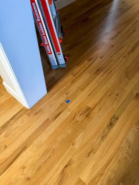 Castle Rock, Colorado, ABD-26 Nisan 2023-A ahşap zemin, belli bir noktayı gösteren küçük bir mavi bant ile ahşap kalasların sıcak doğal bir tonu ve pürüzsüz cilalı bir merdiveni var.