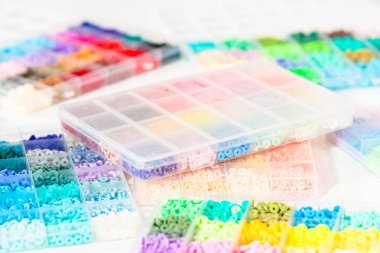 Beyaz bir masaya yerleştirilmiş çeşitli kil boncuk kutuları yaratıcı çocukların el sanatları projesini bekliyor..