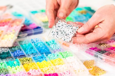 Beyaz bir masaya yerleştirilmiş çeşitli kil boncuk kutuları yaratıcı çocukların el sanatları projesini bekliyor..