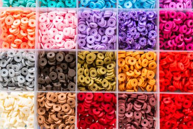 Beyaz bir masaya yerleştirilmiş çeşitli kil boncuk kutuları yaratıcı çocukların el sanatları projesini bekliyor..