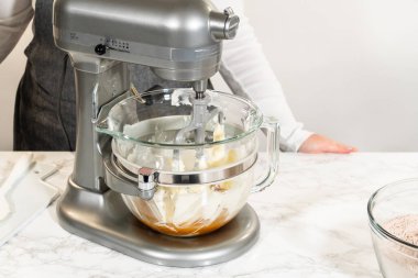 Tereyağı, esmer şeker ve ince baharatlı zencefilli kurabiyeler için diğer malzemelerle karıştırın. Mikserdeki cam kase kısmen dolu..