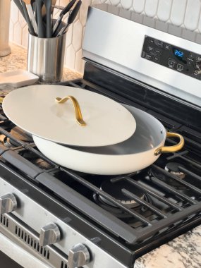 Castle Rock, Colorado, ABD-18 Ocak 2025-Altın saplı beyaz bir tencere ve bir eşleşen kapağı bir gaz sobasının üzerinde duruyor.