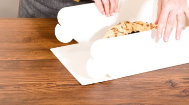 Tuzlu karamel şekerlemeleri ve zencefilli ekmek parçacıklarıyla süslenmiş zencefilli keki dikkatlice hediye etmek için açık pencereli beyaz bir kağıt bohça kek kutusuna yerleştiriyorum..