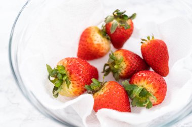 Taze yıkanmış ve kurutulmuş çilekler kağıt havluyla kaplı cam bir kasede dikkatlice düzenlenir. Atıştırmaya ya da daha fazla kullanılmaya hazır hale getirilir..