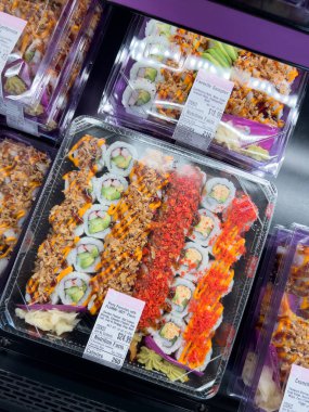 Süpürge, Colorado, ABD-8 Şubat 2025 - Temiz plastik kaplarda paketli taze suşi ruloları bir markette soğutulmuş bölümde sergilenmektedir