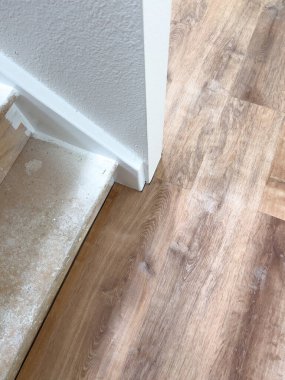 Tadilattan geçen bir merdiven. Tahta basamakları toz ve enkazla gösteriyor. Çevreleyen beyaz duvarlar ve yeni döşenmiş ahşap döşemeler devam eden bir ev geliştirme projesini gösteriyor.