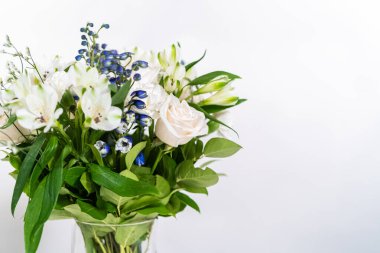 Taze beyaz güllerin ve çeşitli çiçeklerin bulunduğu büyüleyici bir buket, zarif bir vazoda düzenlenmiş, zamansız bir güzellik yayıyor..