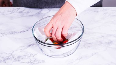 Çilekler, yeni yıkanmış ve kurutulmuş, cam bir kasede güzelce depolanmış kağıt havluyla kaplanmış ve tazeliği korumak için plastikle kaplanmış..