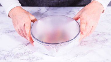 Çilekler, yeni yıkanmış ve kurutulmuş, cam bir kasede güzelce depolanmış kağıt havluyla kaplanmış ve tazeliği korumak için plastikle kaplanmış..