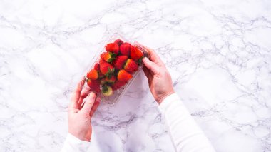 Düz yatıyordu. Taze çilekler, mutfak tezgahında dinlenen ve yıkanmaya, yenmeye ya da saklanmaya hazır orijinal plastik konteynerlerinde sergilenir..