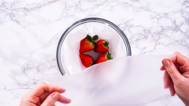 Düz yatıyordu. Çilekler, yeni yıkanmış ve kurutulmuş, cam bir kasede güzelce depolanmış kağıt havluyla kaplanmış ve tazeliği korumak için plastikle kaplanmış..